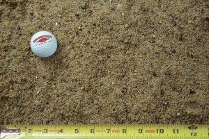 concrete sand shown with a measuring tape and golf ball for size comparison