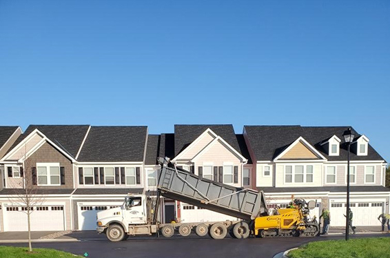 Dump truck loading asphalt into paving machine